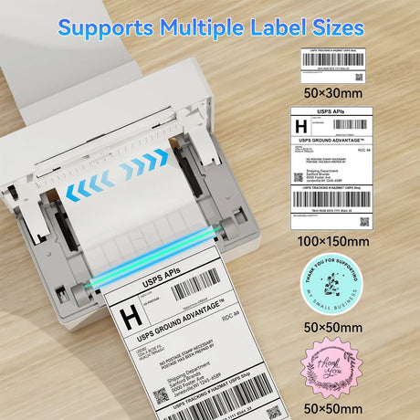 PB 40 Shipping Label Printer in White designed for effortless shipping label printing across iPhone, iPad, Android, Windows, and Mac devices. The package includes the printer, power adapter, USB cable, cords, and user manuals neatly arranged on a wooden table.